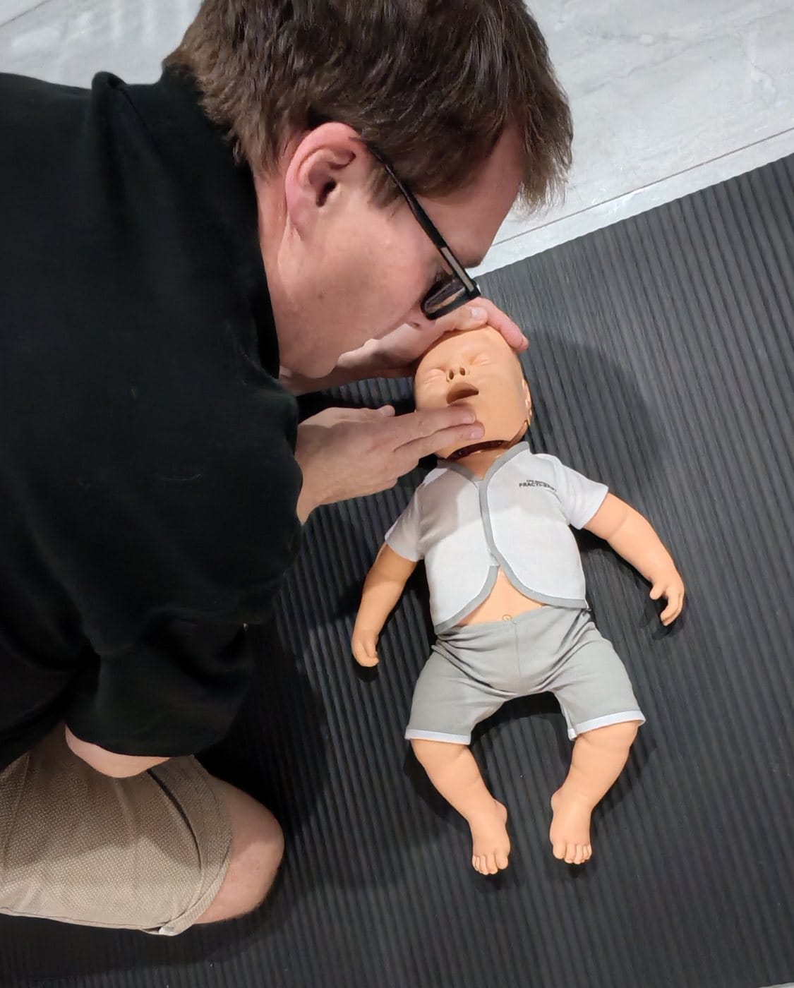 James practising airway positioning with an infant training manikin