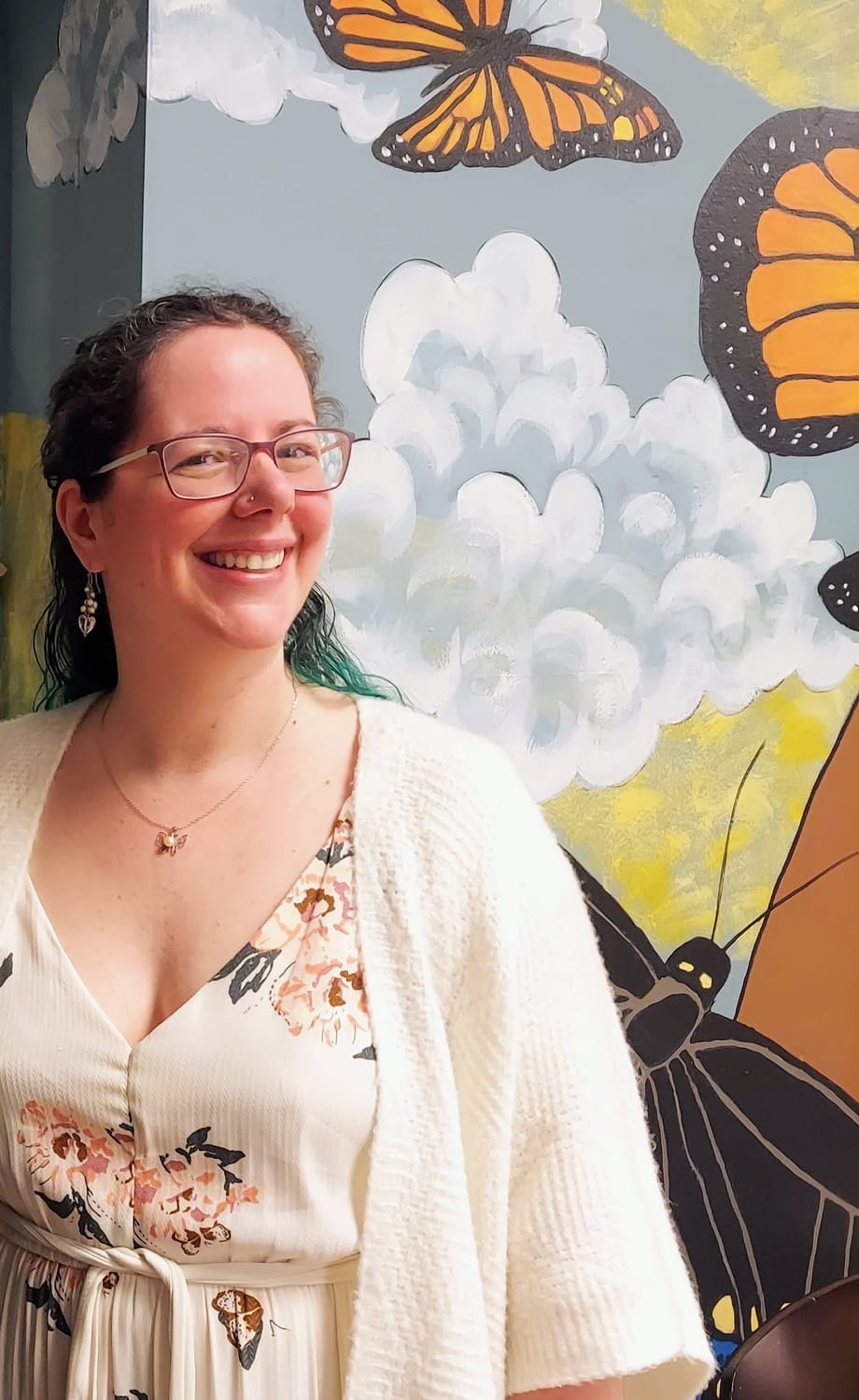 Picture of Jessica smiling in front of butterfly mural