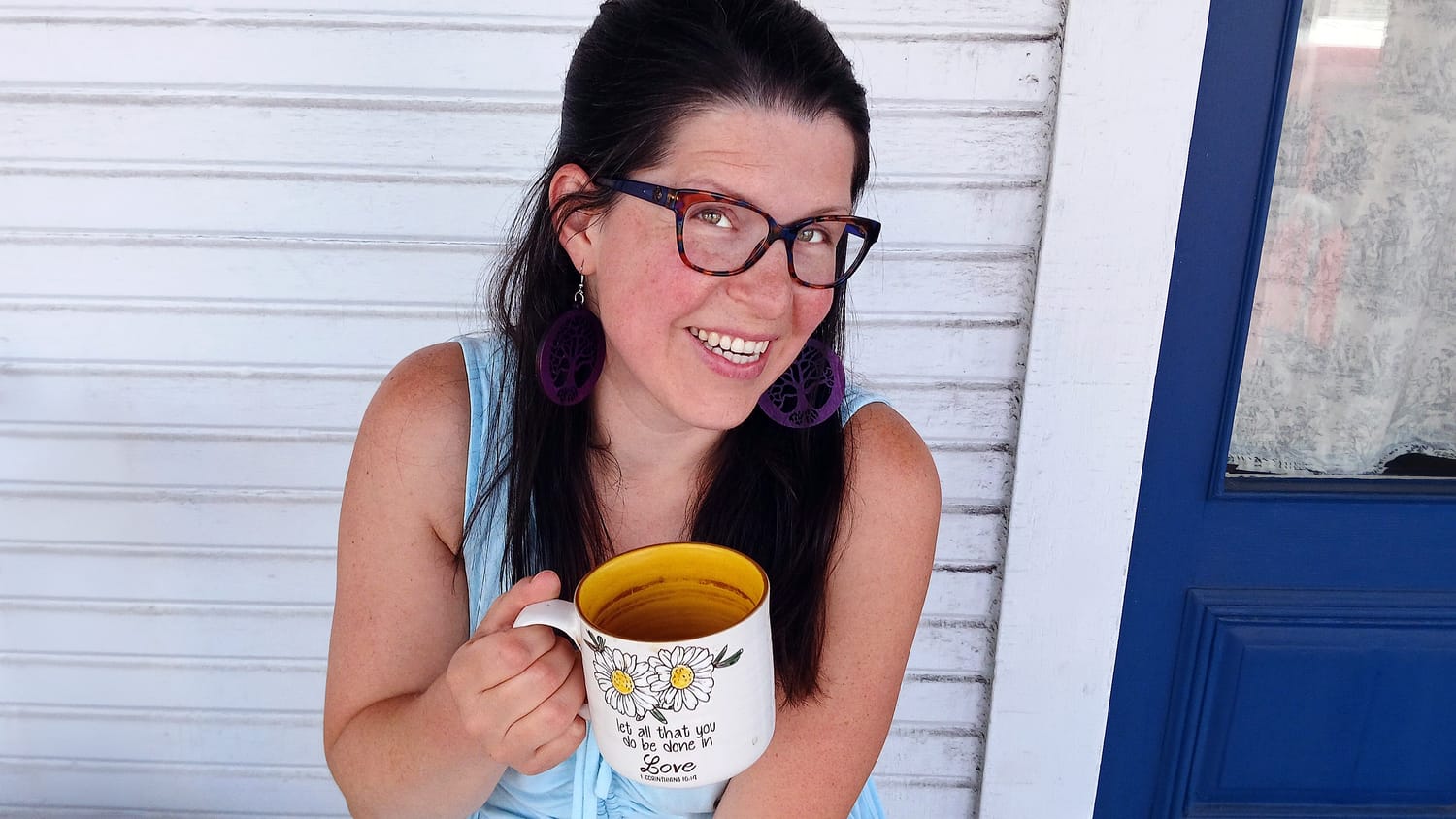 Elissa smiling on her porch with a daisy mug