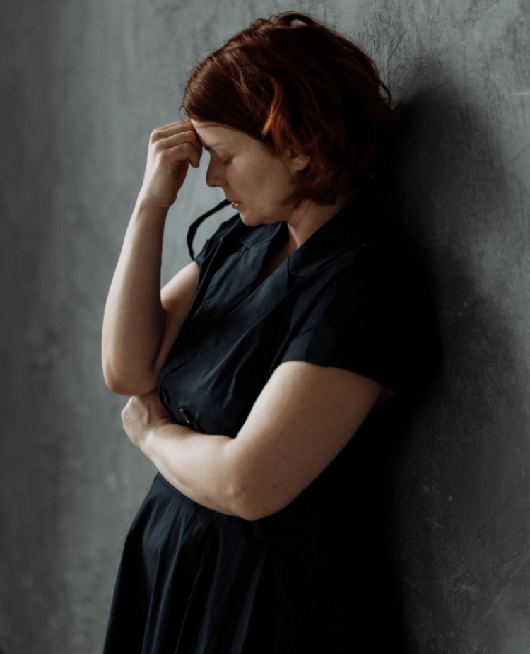 Femme assise contre un mur, semblant préoccupée et épuisée