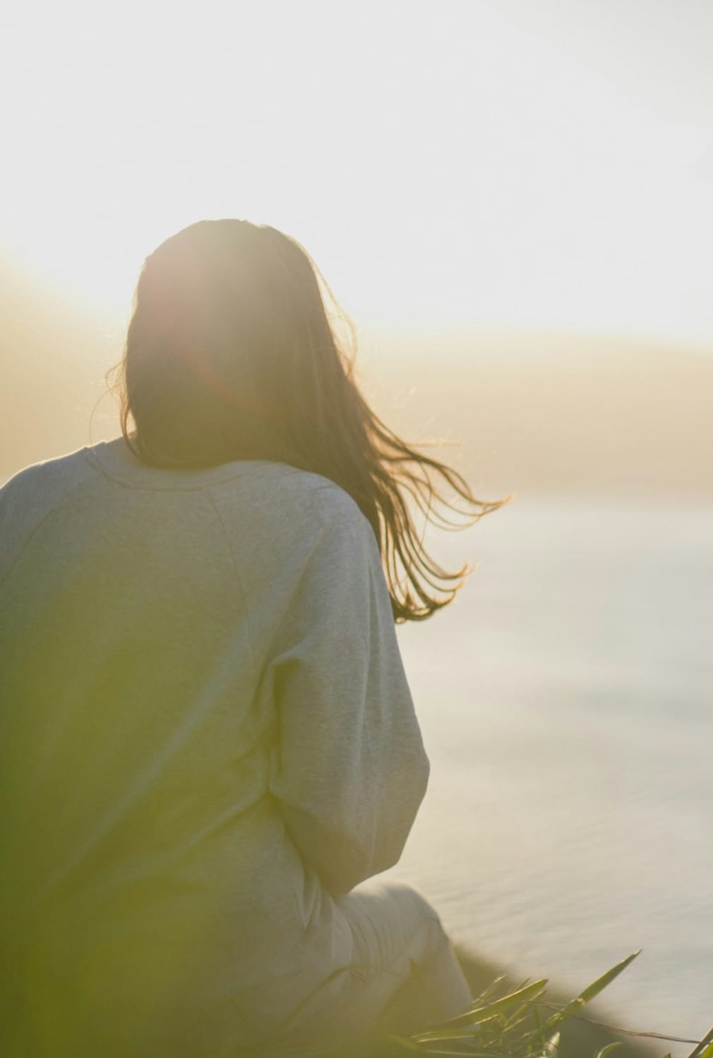 Thoughtful woman with coffee looking at city skyline sunrise.