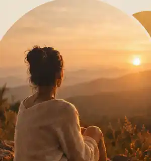 Femme assise face au coucher de soleil