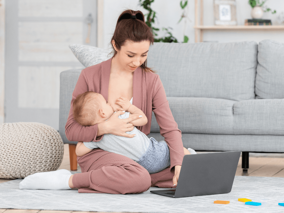 Mutter stillt ihr Baby zu Hause mit Stillwissen auf dem Laptop