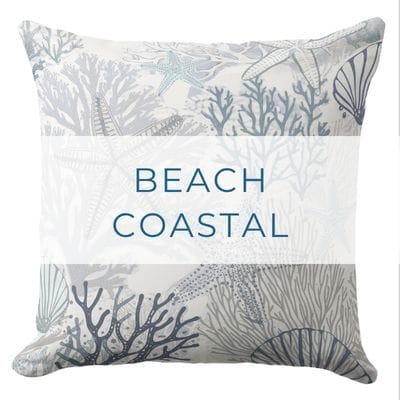A beach throw pillow featuring a muted blue, grey and white coral and starfish pattern.