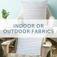 a square white coastal throw pillow with thin blue stripes in coastal style in an indoor and outdoor fabric