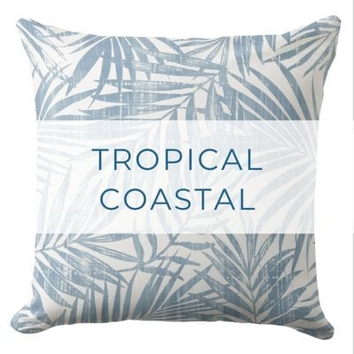 A tropical coastal throw pillow with blue and white tropical palm leaves pattern.