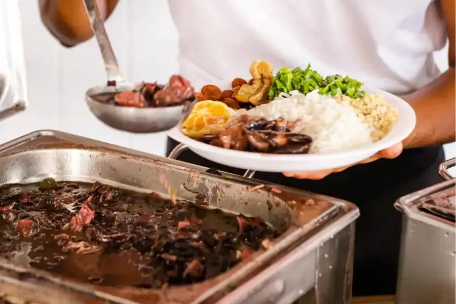 traditional feijoada dish with pork, rice, farofa, green collar and orange served at Cacique de Ramos