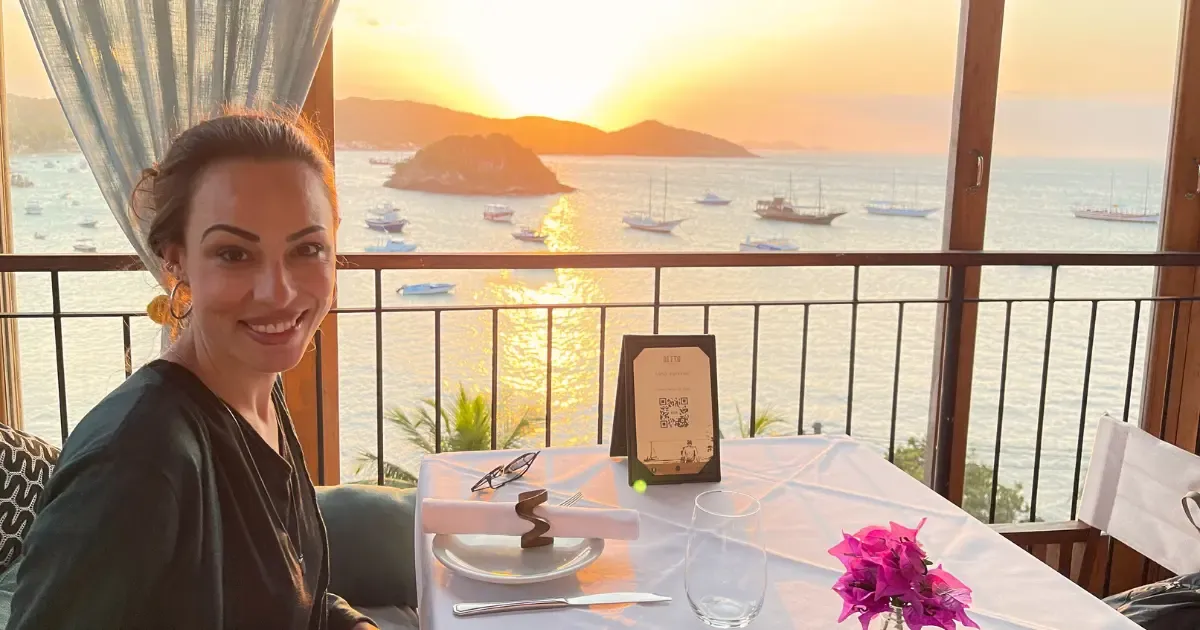 Michele at Mistico restaurant table next to a window for the sunset in Buzios, Rio de Janeiro State