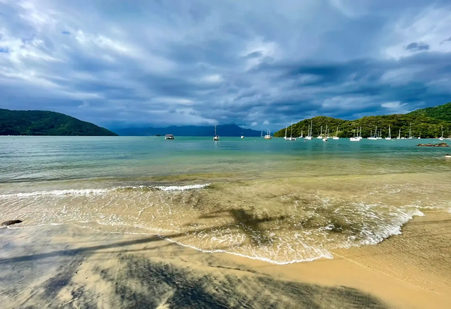 view of Abraao village calm beach with boats in Ilha Grande for a day trip in Rio de Janeiro State