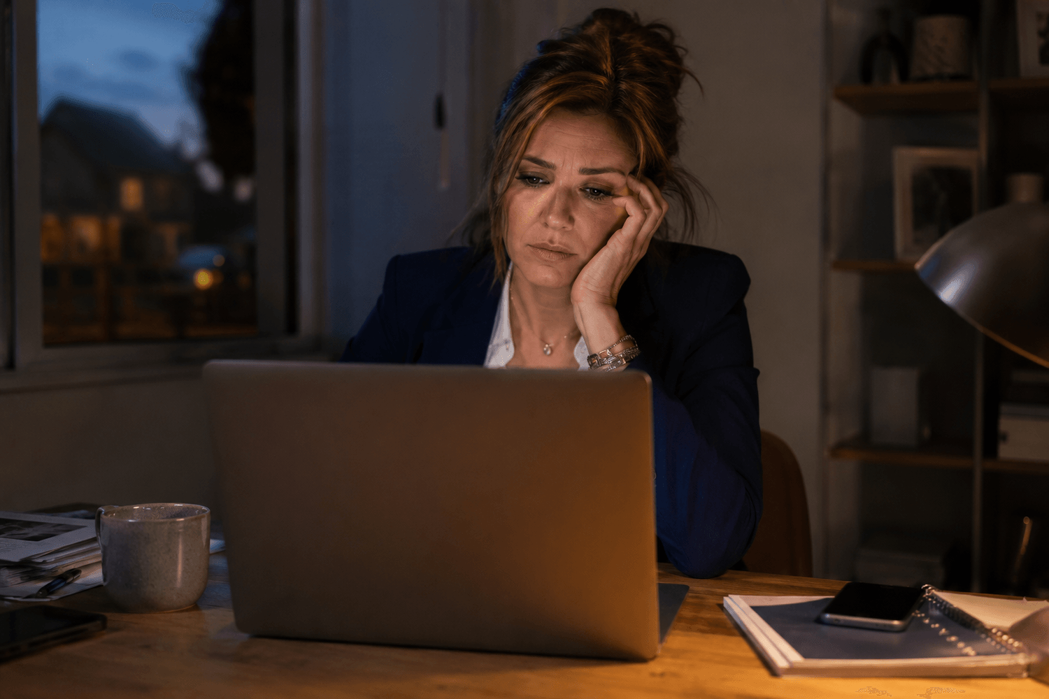 Realtor at her desk looking at a full CRM screen, conflicted