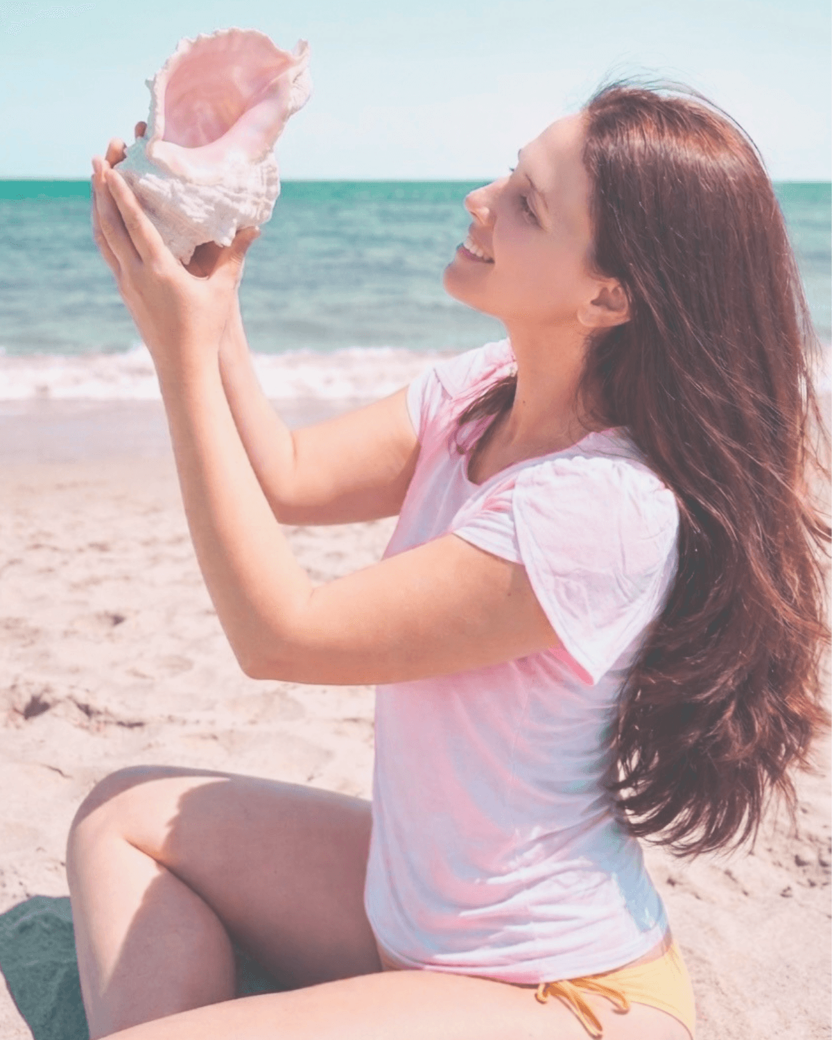 Femme écoutant un coquillage sur la plage
