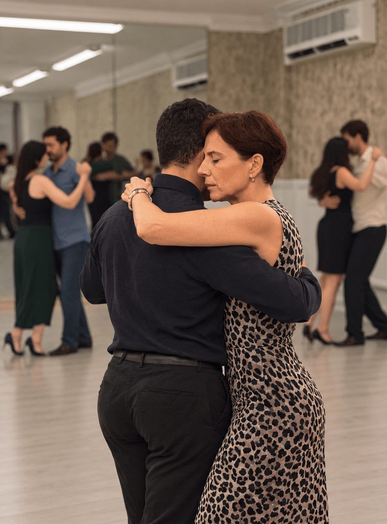 A couple dancing close in Argentine Tango with other dancers behind them
