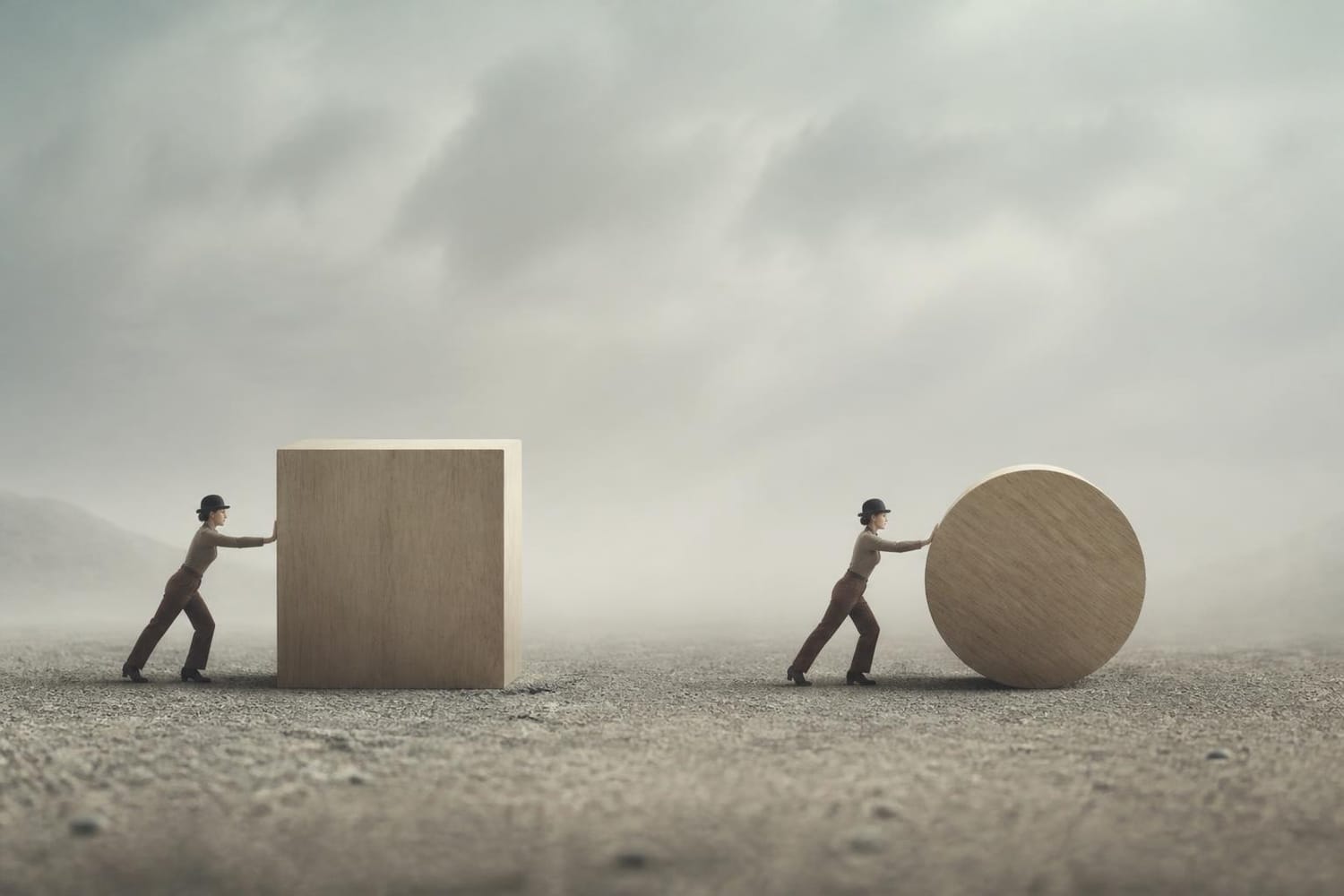 Two small figures in bowler hats, each pushing a huge wooden shape, a cube and a disc, across a foggy gray plain.