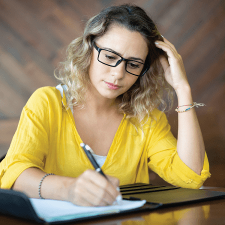 Frustrated female business owner taking notes while analyzing why her  email flows and customer journey aren't converting traffic into consistent  revenue.