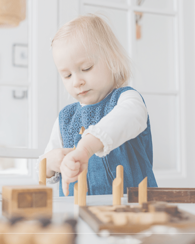 three year old playing with wooden pegs