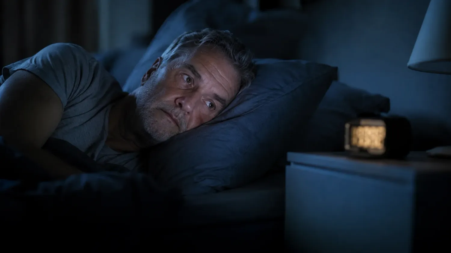 A man in his late 50s lying awake at night