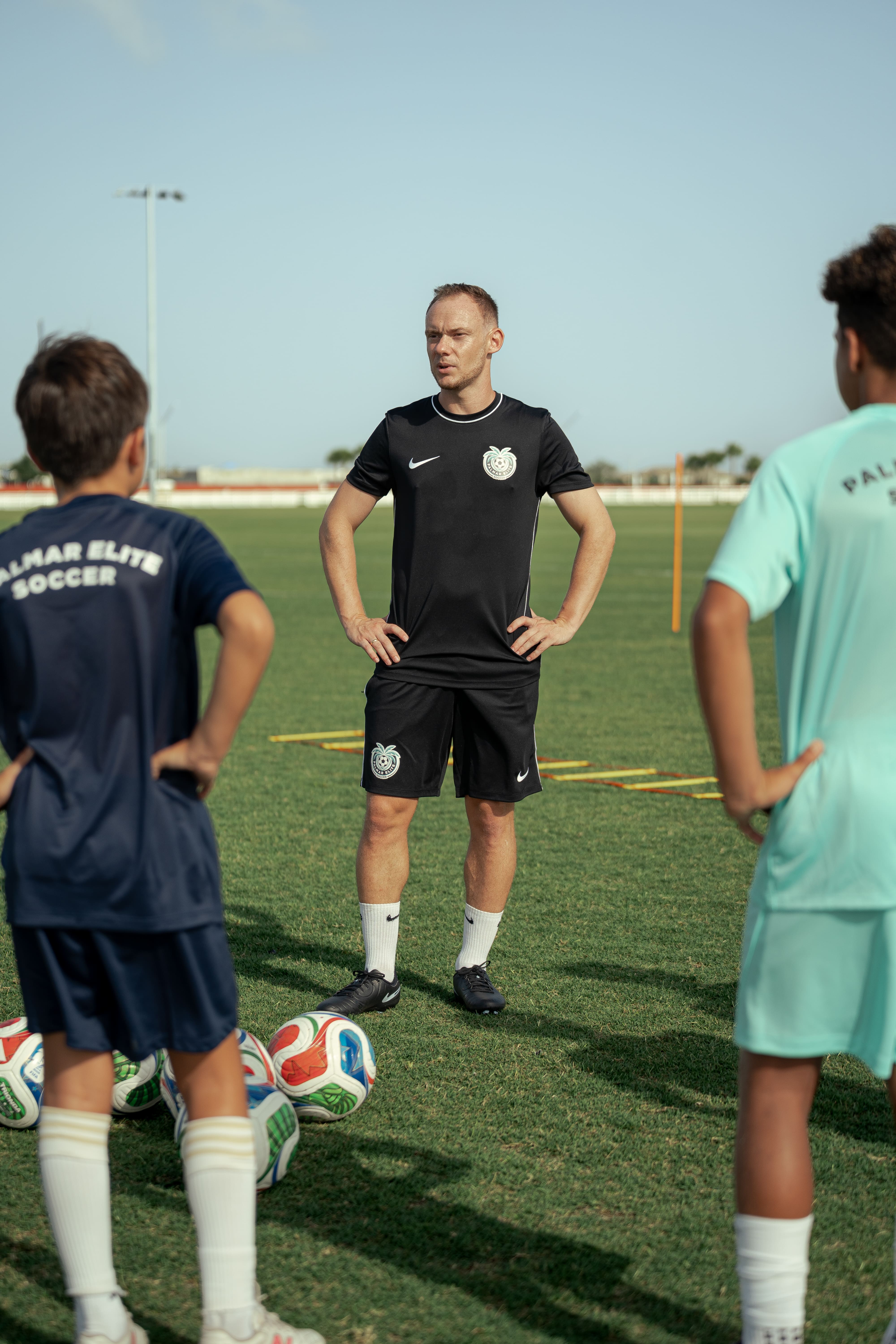 Federico standing on the training field with two young players