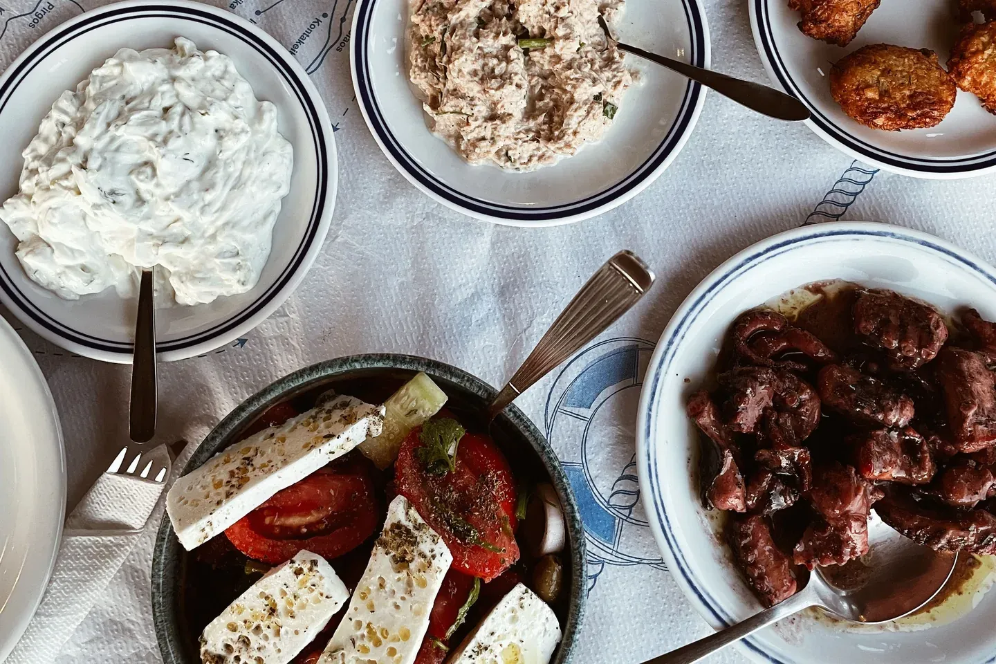 Shared Greek taverna table with meze and dishes