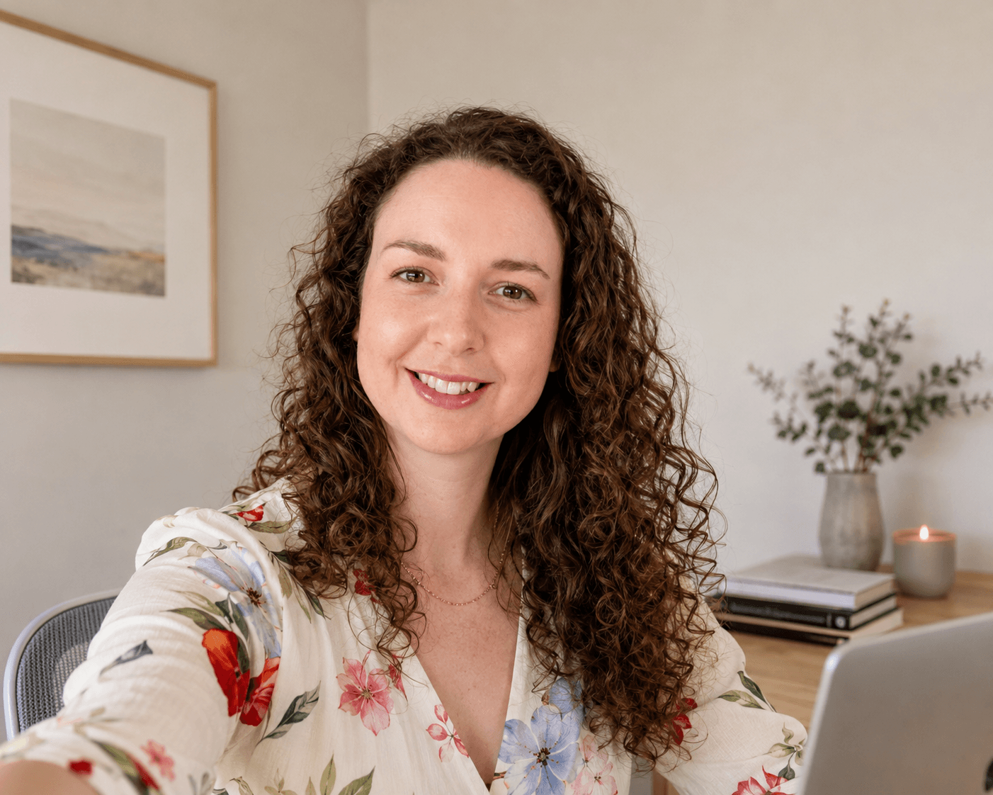A woman smiling at her desk in a bright, calm home office