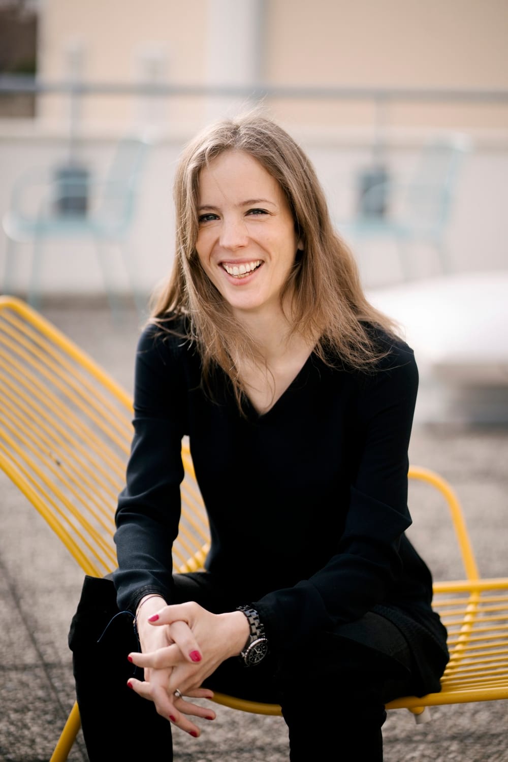 Marie Chevrier, souriante, assise sur une chaise jaune en terrasse