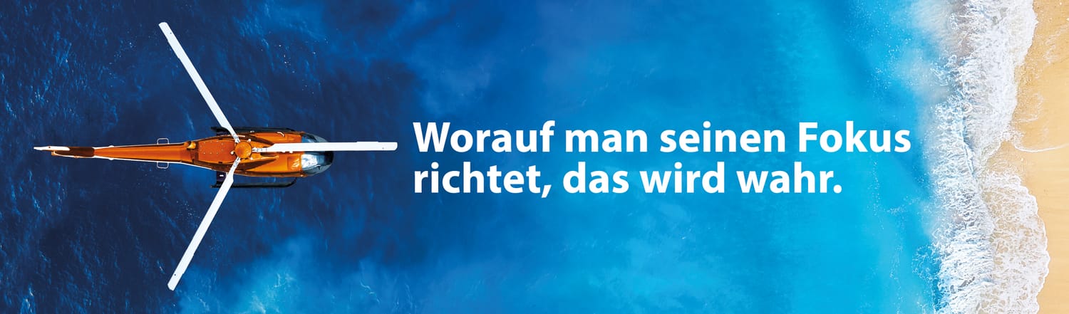 Heli über dem Meer mit dem Spruch: Worauf man seinen Fokus richtet, das wird wahr.