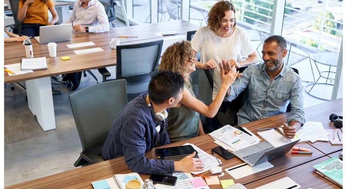 Colleagues working together at a long table in a bright open office