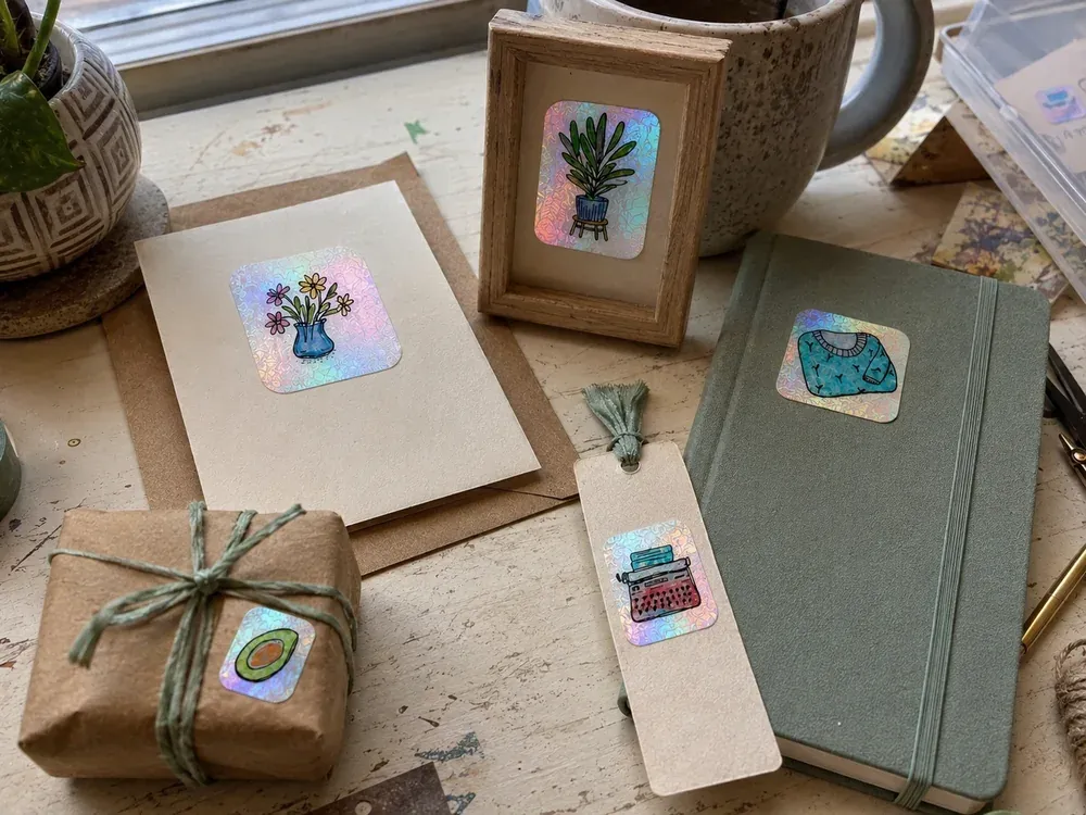 A candid craft table with a handmade card, framed drawing, journal, bookmark, and gift wrap