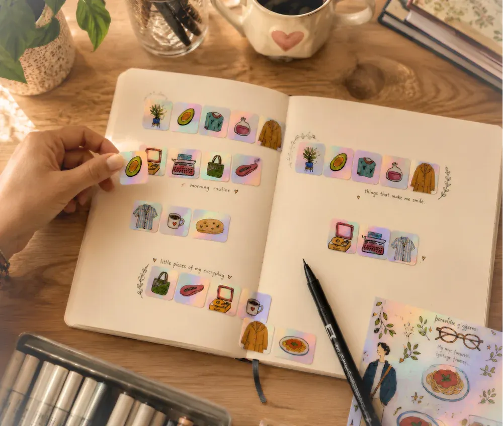 Open notebook pages filled with small shimmering illustrations of everyday moments