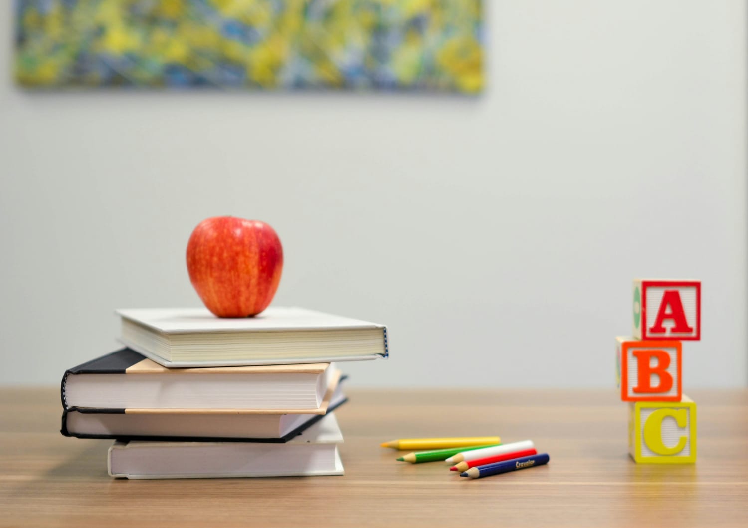 Books with an apple on top colored pencils and blocks ABC on the right side.
