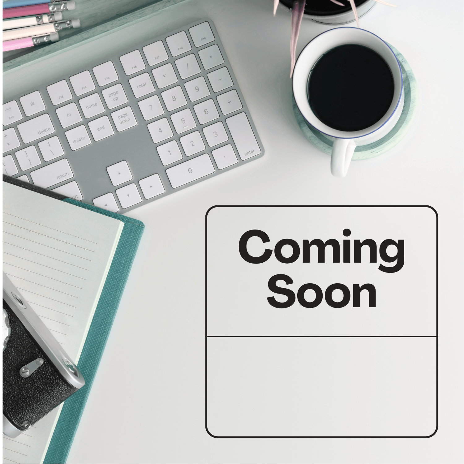 Keyboard with blue notebook and coffee mug. Coming Soon title.