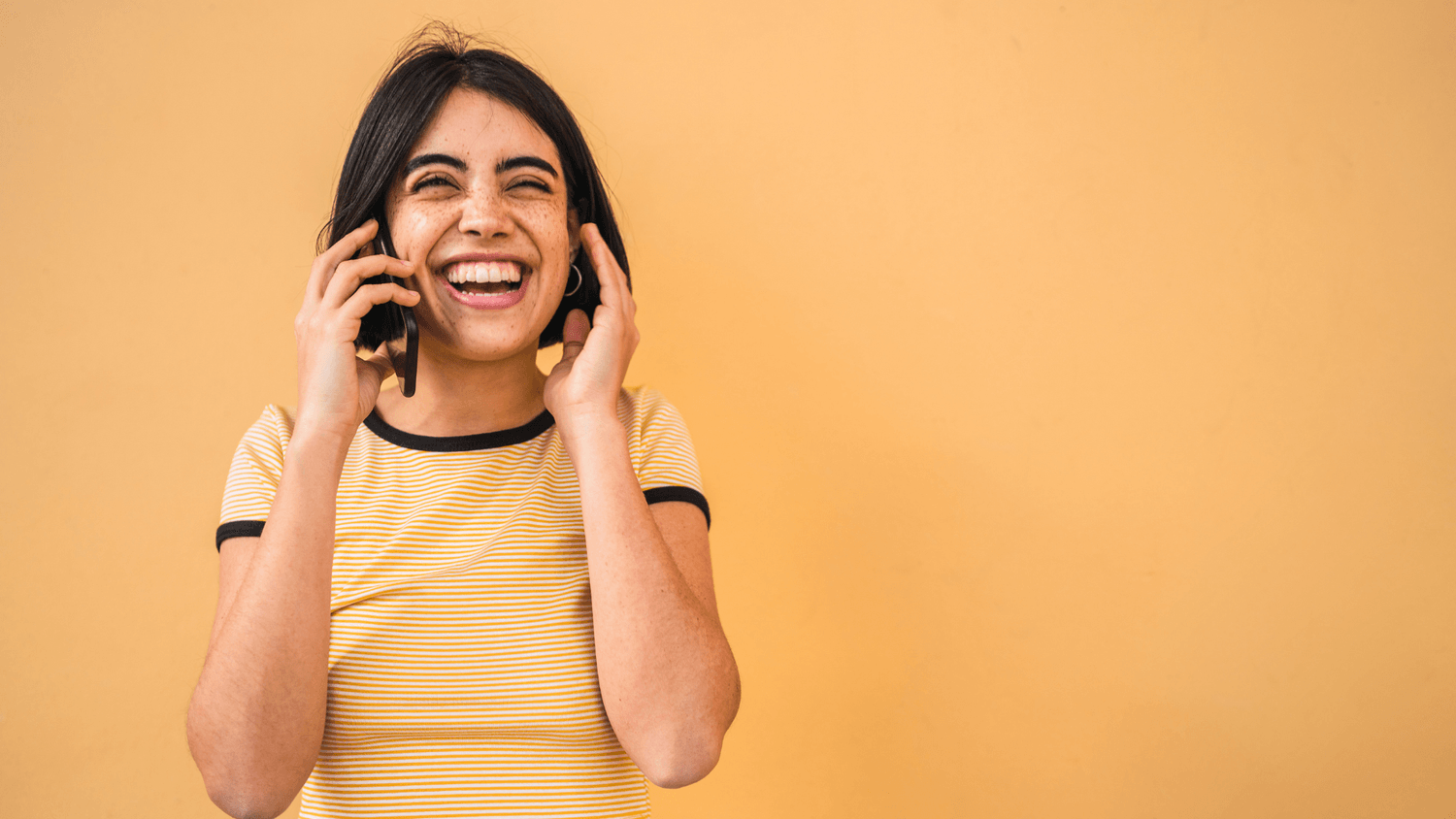 Woman on a phone wearing orange tshirt against orange background