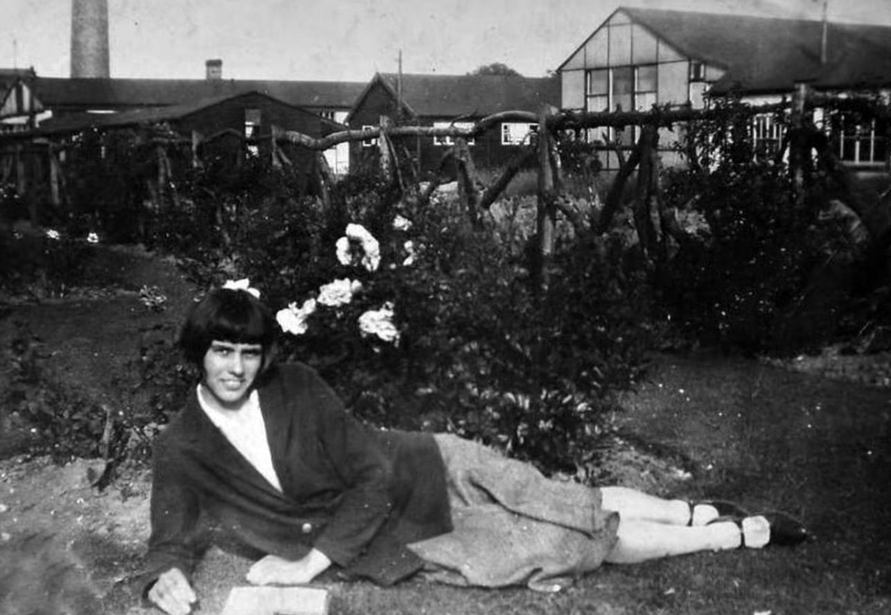 emily kathleen renshaw lays on grass with a fence and houses behind her. The inspiration behind ablepreneurs and national ablepreneurs day