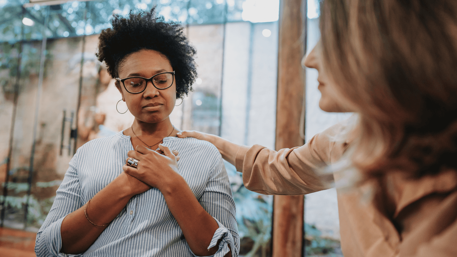 a lady sits with her hands on her chest with her etes closed. ANother lady has her hand on her shoulders to comfort her. Ablepreneurs trusted partner page.