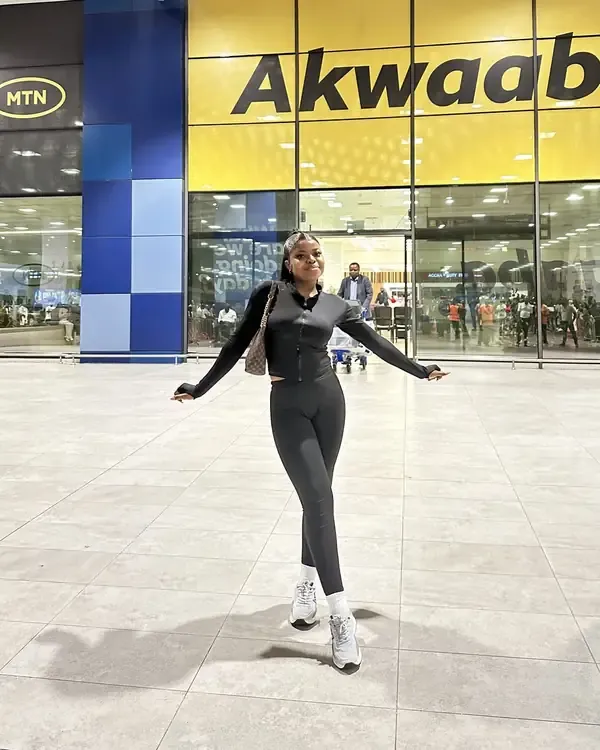 Geraldine in a black outfit at the airport, arms out wide