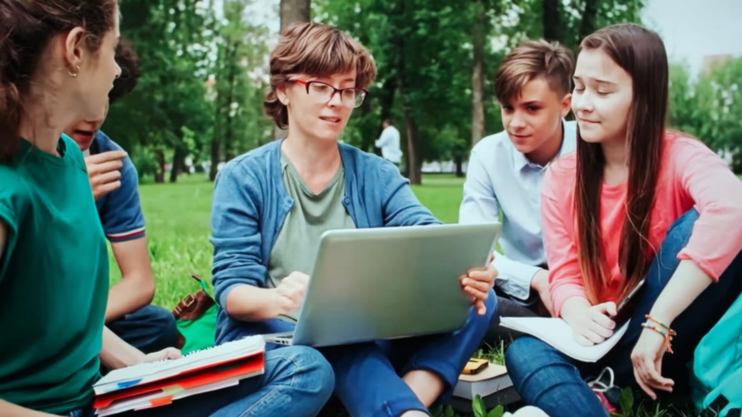 Group of students studying together outdoors with a laptop