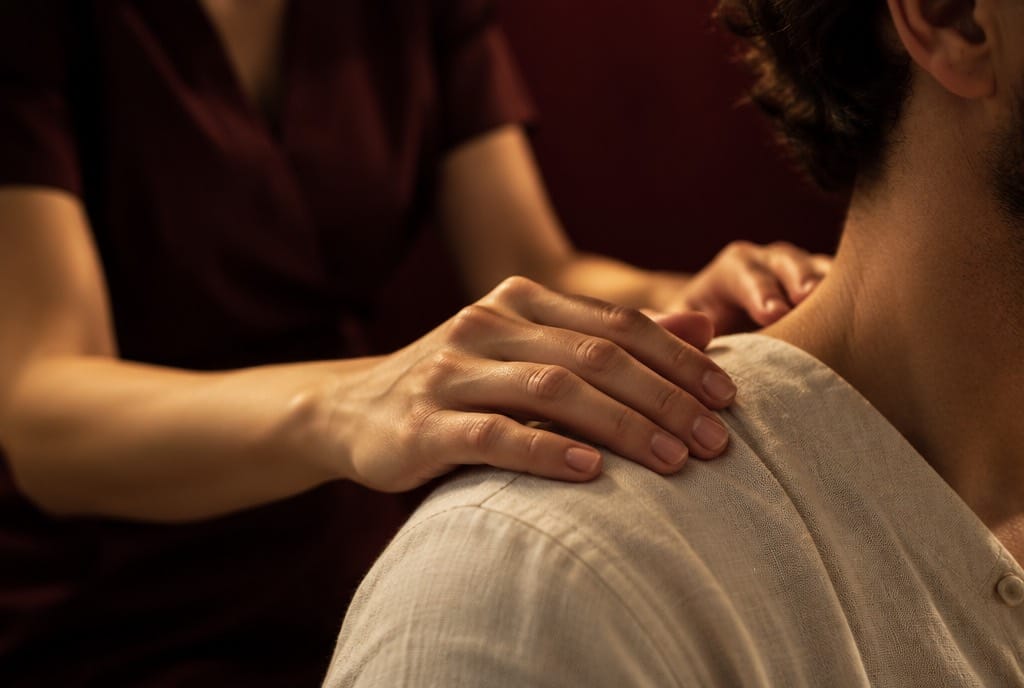 Le mani di un'operatrice appoggiate sulla spalla di una persona, con un gesto ancora incerto