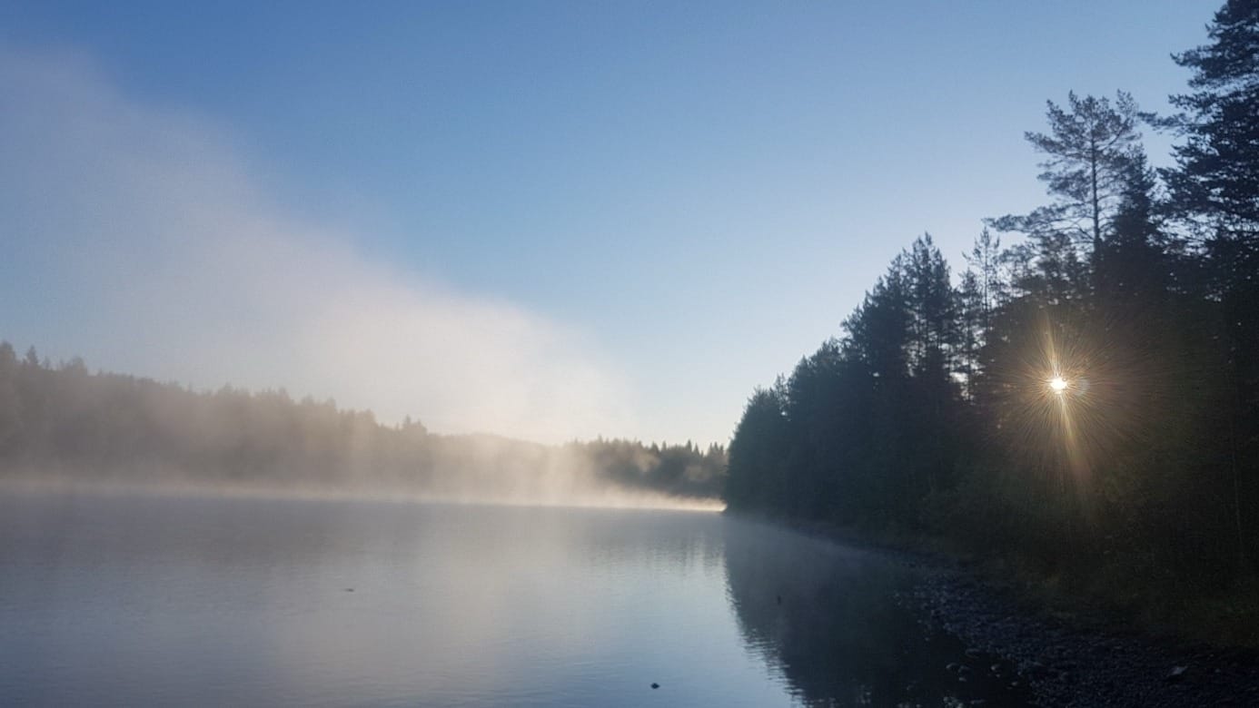 Dimmig soluppgång som speglar sig i vattnet vid Auszeit-Oase