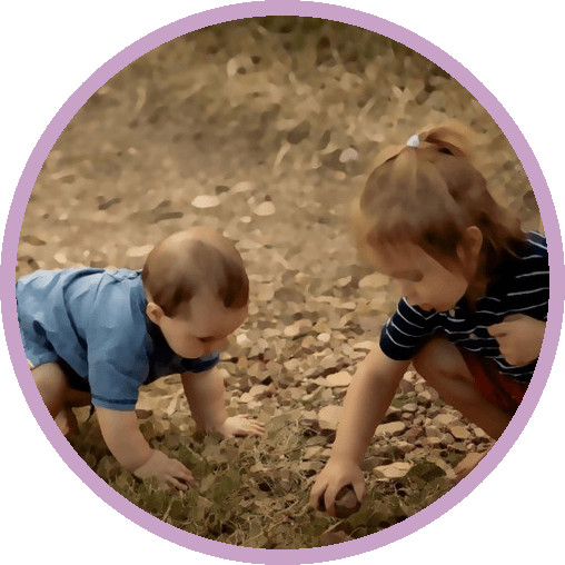 Two children crouching to look at something among the stones