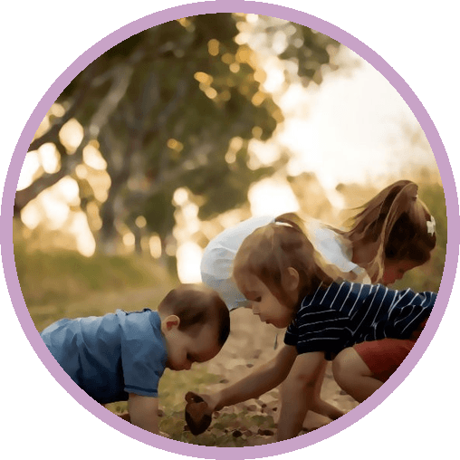 Two children crouched on a path, looking closely at the ground