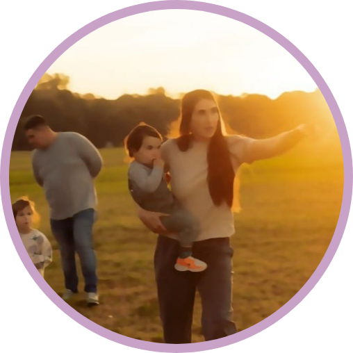 Jess holding her son in a sunlit field