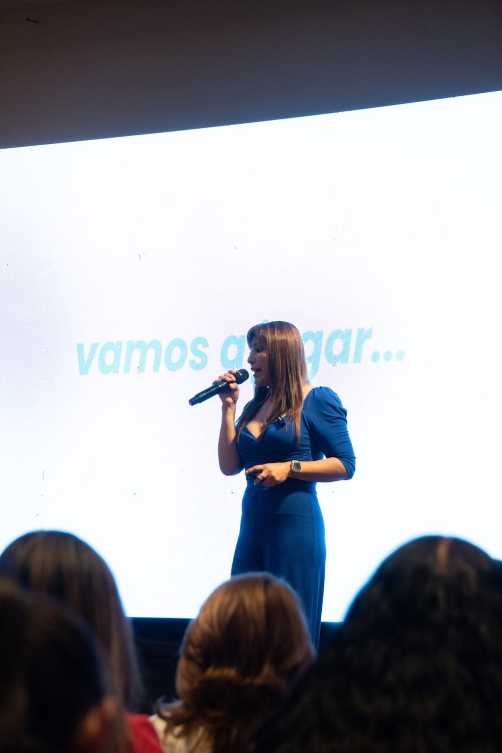 Carolina Flores Madrid hablando en un escenario con vestido azul