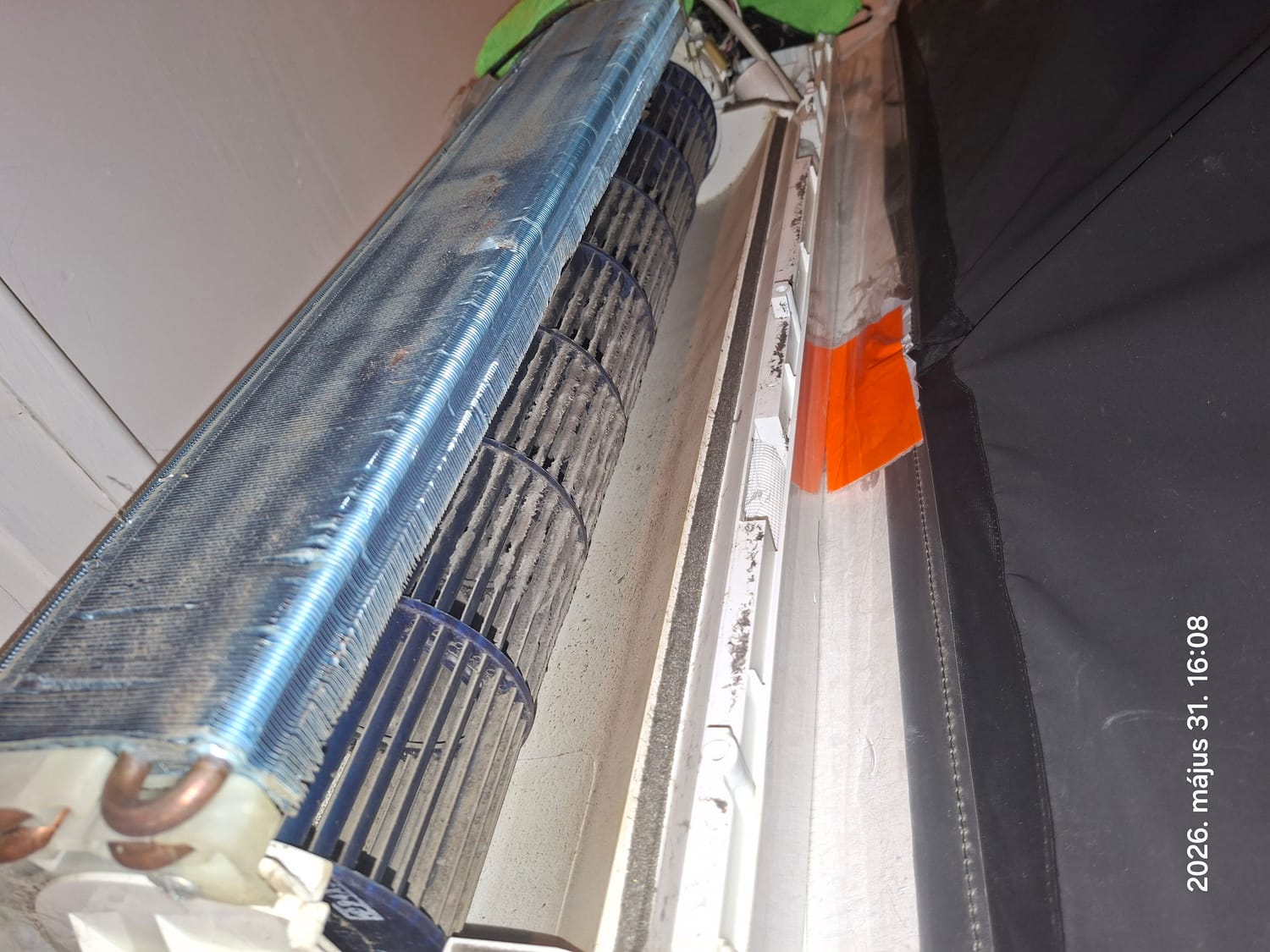 Falra szerelt beltéri egység szétnyitva, a hőcserélő és a ventilátor alatt gyűjtőfólia
