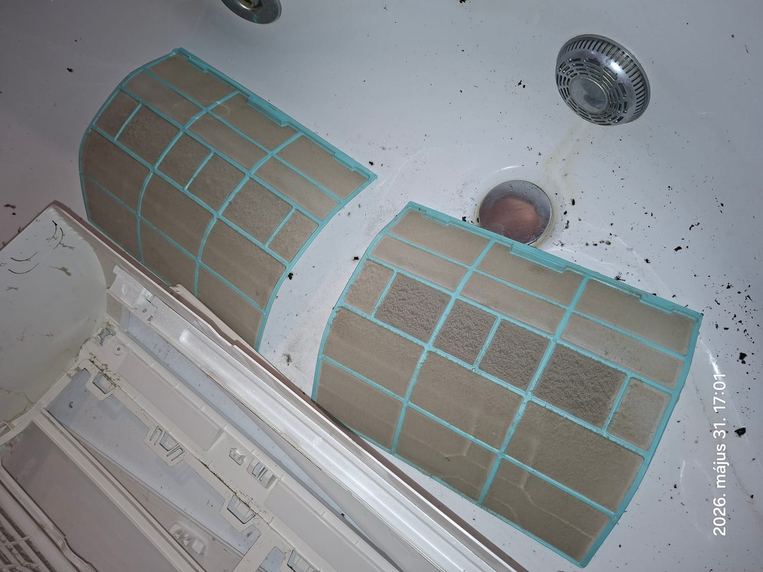 Két poros légszűrő a kádban, mellettük a beltéri egység előlapja