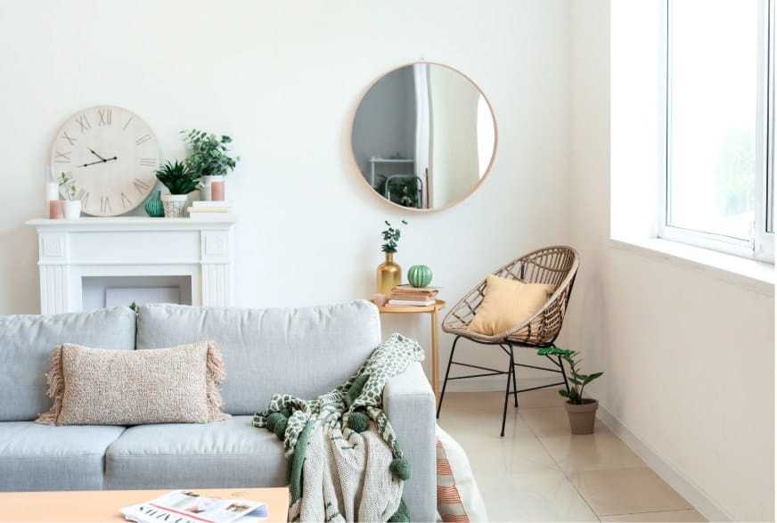 A calm, lived-in living room with a round mirror, a sofa and plants