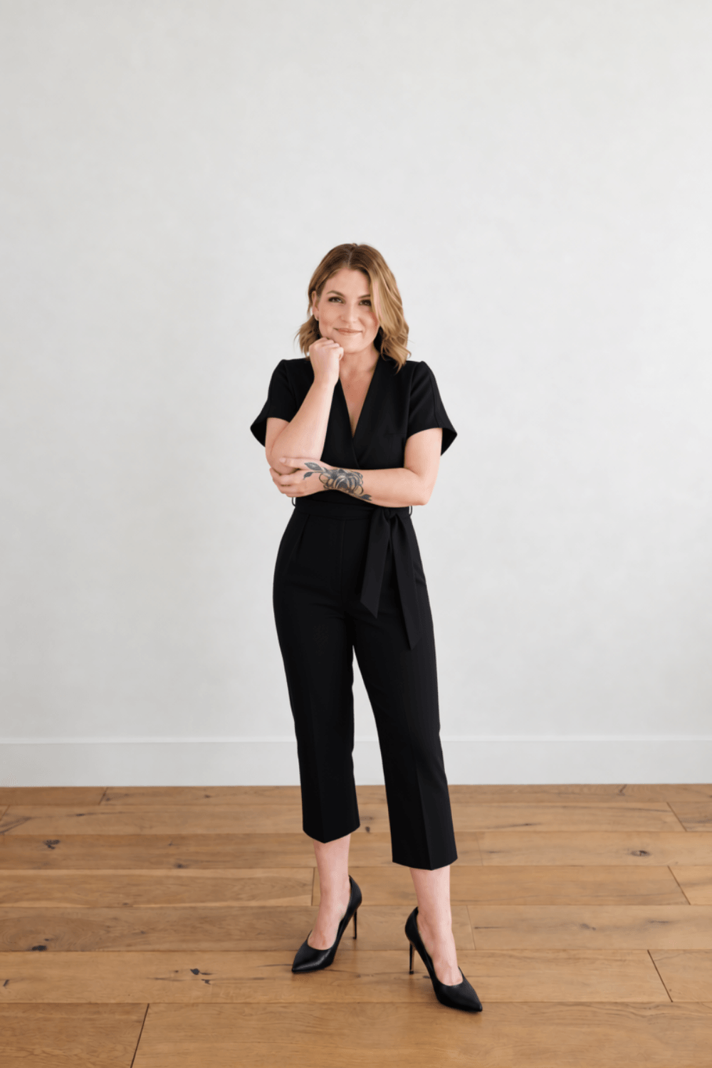Blair Lindsay in a black outfit, smiling with her chin resting on her hand.