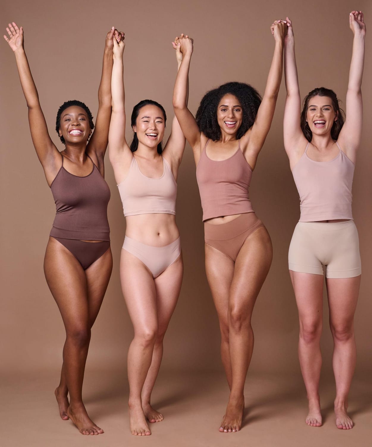 quatre femmes heureuses qui se tiennent la main en tenue de sport