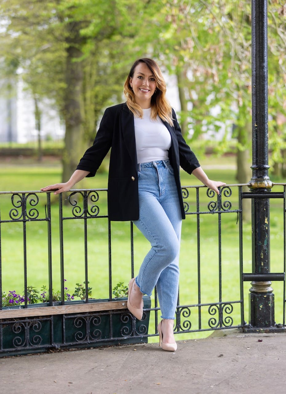 Lauren Bell leaning on a park railing, smiling