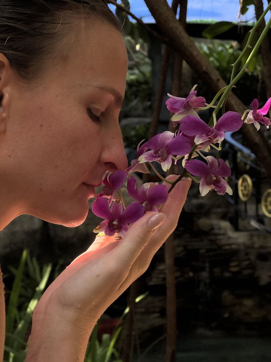 Nadia riecht mit geschlossenen Augen an einer Orchidee