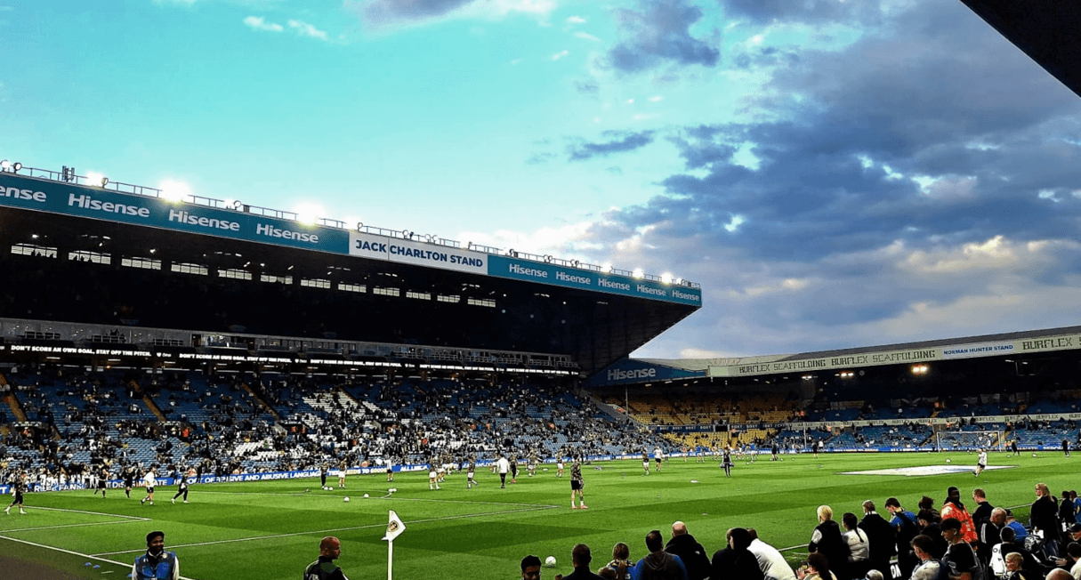 Supporters filling the Jack Charlton Stand at Elland Road beneath a cloudy sky.