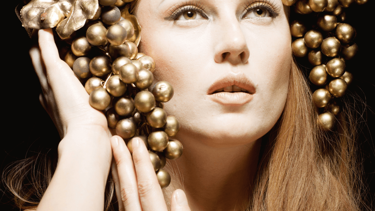 Femme inspirée de l’Antiquité grecque, entourée de grappes dorées, symbolisant la pleine conscience, la sérénité et la résilience intérieure